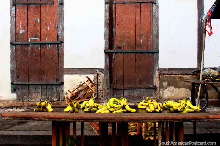 Yellow bananas and 2 old brown wooden doors after markets close in Cayenne, French Guiana. (720x480px). The 3 Guianas, South America.