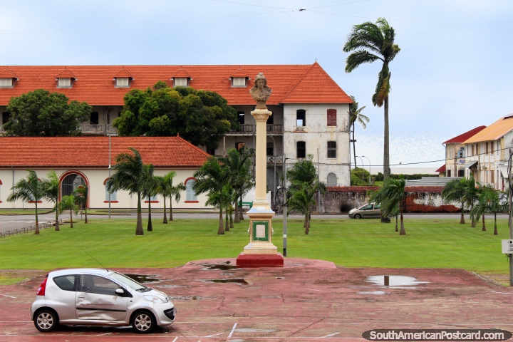 Old and new buildings with tiled roofs and a monument, the sea behind, Cayenne, French Guiana. (720x480px). The 3 Guianas, South America.