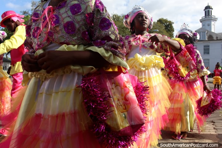 Libi Trobi Krioro, as meninas vestiram-se em ouitfits amarelo, rosa, cor-de-laranja e purpúreo na pompa de Avondvierdaagse em Paramaribo, Suriname. (720x480px). As 3 Guianas, América do Sul.