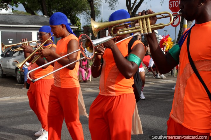 Trompetistas vestidos de naranja con la cabeza azul envuelve en el desfile Avondvierdaagse en Paramaribo, Surinam. (720x480px). Las 3 Guayanas, Sudamerica.