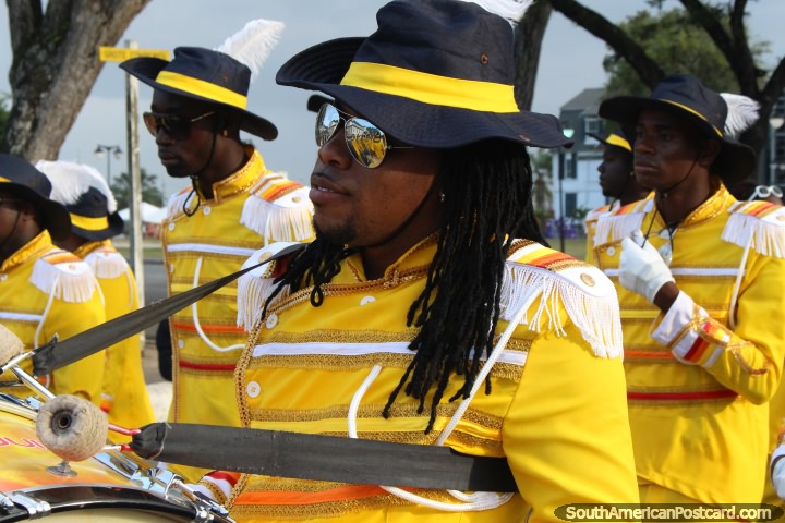 Drummer man with plaited hair and dressed in yellow at the Avondvierdaagse parade in Paramaribo, Suriname. (720x480px). The 3 Guianas, South America.