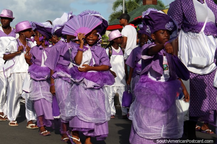 As crianças vestiram-se em púrpura e branco, alguns com torcedores, a pompa de Avondvierdaagse em Paramaribo, Suriname. (720x480px). As 3 Guianas, América do Sul.