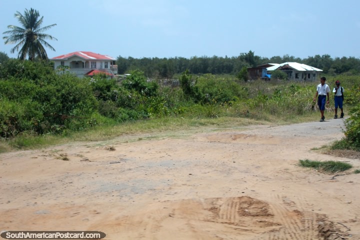 Un par de nios de la escuela a pie en un camino rural entre Nueva Amsterdam y Georgetown, en Guyana. (720x480px). Las 3 Guayanas, Sudamerica.