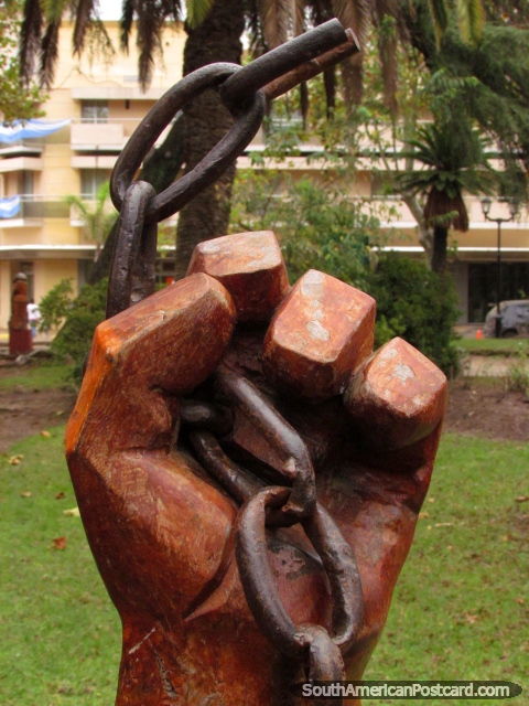 Hand holding chain wooden sculpture at Plaza San Martin in Colon. (480x640px). Argentina, South America.