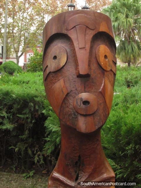 Mask-like wooden sculpture at Plaza San Martin in Colon. (480x640px). Argentina, South America.