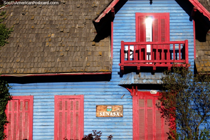Casa de madeira de azul com balco vermelho, portas e janelas e um telhado coberto com telhas, em Bariloche. (720x480px). Argentina, Amrica do Sul.