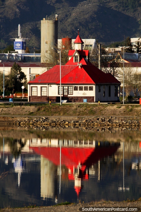 Museo Casa Beban con techo rojo brillante y la torre se refleja en el agua en Ushuaia. (480x720px). Argentina, Sudamerica.