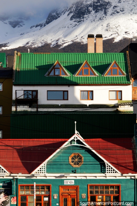 Shop below and a house above with mountains behind them in Ushuaia. (480x720px). Argentina, South America.