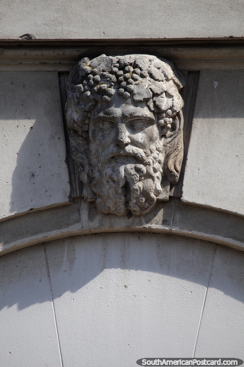 Bearded man with grapes in his hair, stone face, facade of church, Bahia Blanca. (480x720px). Argentina, South America.