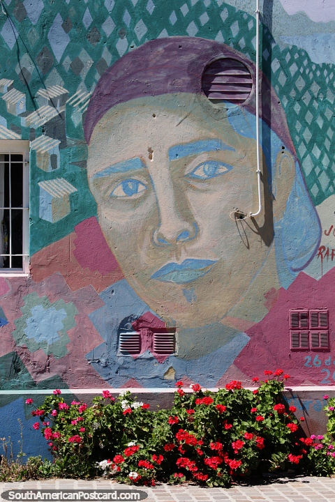 Colorful street art above a colorful garden of flowers in Trelew. (480x720px). Argentina, South America.