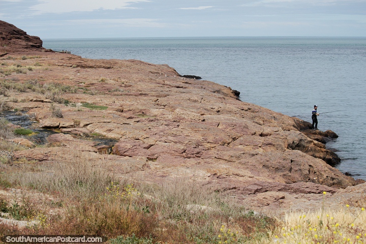 Um pescador  beira das rochas, litoral em Puerto Deseado. (720x480px). Argentina, Amrica do Sul.
