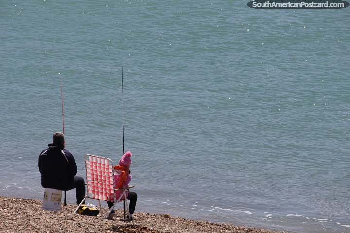 Father and daughter fishing while sitting beside the sea in Puerto San Julian. (720x480px). Argentina, South America.