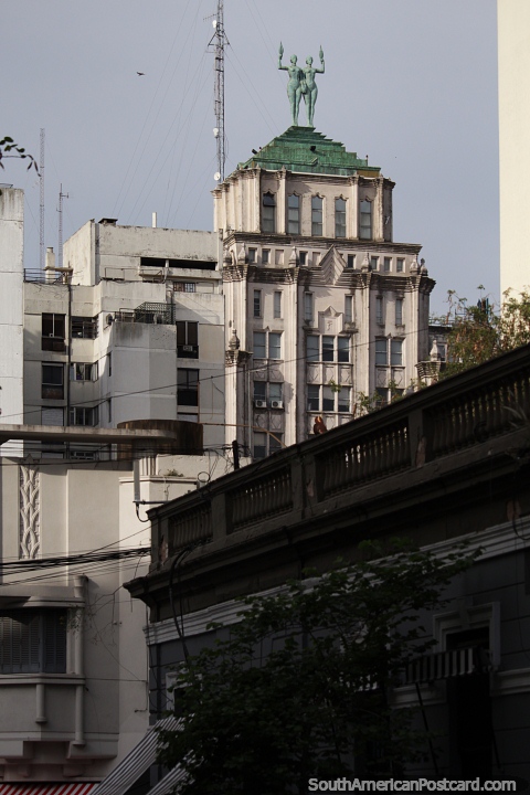 Un par de figuras femeninas sostienen antorchas con llamas en el techo de este edificio en Rosario. (480x720px). Argentina, Sudamerica.
