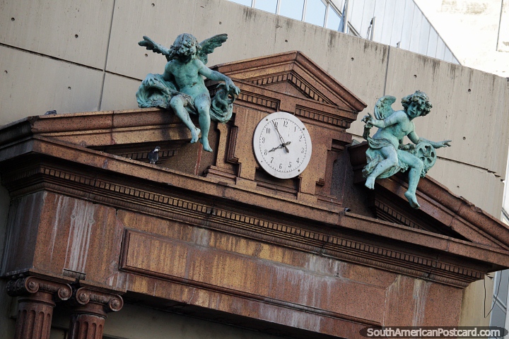 Par de anjos verde-bronze em cada lado de um relógio, um monumento em Rosário. (720x480px). Argentina, América do Sul.