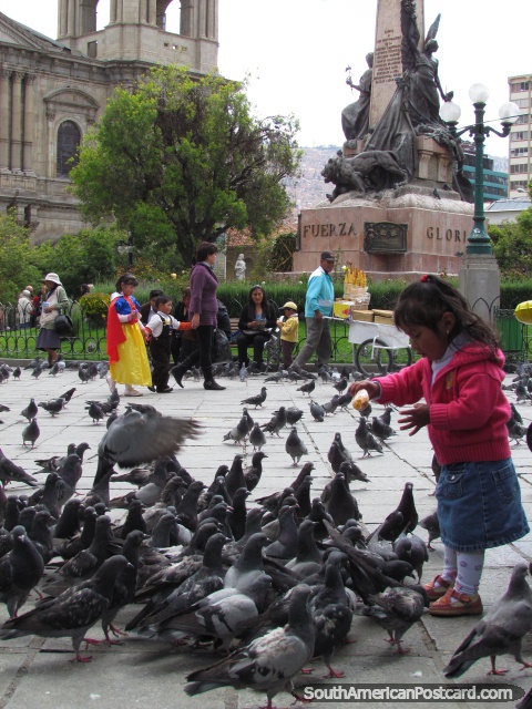 Little girl feeds pigeons in the park in La Paz. (480x640px). Bolivia, South America.