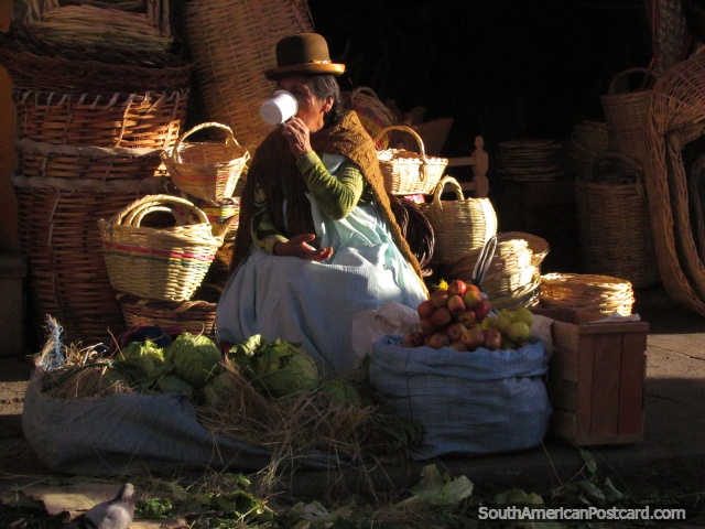 Woman drinks tea at market, baskets, apples and lettuces. (640x480px). Bolivia, South America.