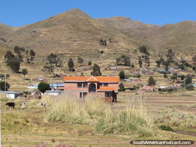 Um edifcio de tijolos cor-de-laranja e fazenda em baixo das colinas entre Guaqui e Desaguadero.  (640x480px). Bolvia, Amrica do Sul.