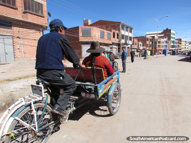 O txi da bicicleta transporta uma mulher ao longo da rua em Desaguadero. (640x480px). Bolvia, Amrica do Sul.