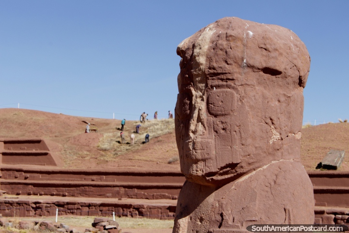 A crumbly stone head, people excavating on the hill behind, Tiwanaku Ruins. (720x480px). Bolivia, South America.
