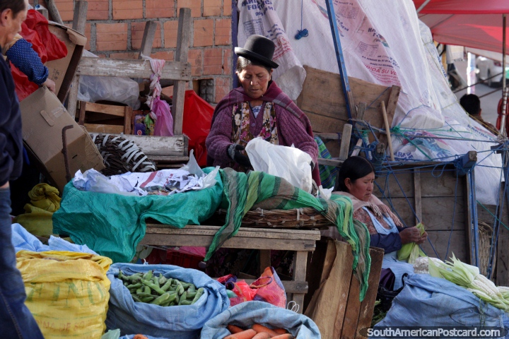 2 women prepare vegetables to sell at the market in La Paz, one peels corn cobs. (720x480px). Bolivia, South America.