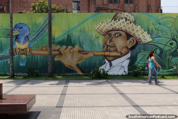 Hombre en un sombrero de paja sopla una flauta de madera, pjaro se sienta en el extremo, mural en Santa Cruz. (720x480px). Bolivia, Sudamerica.