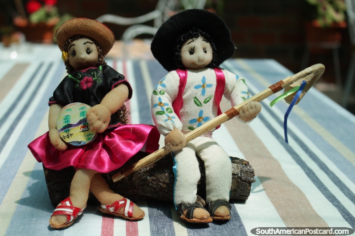 Um par de figuras de boneca que se sentam em um log em Tarija. (720x480px). Bolívia, América do Sul.