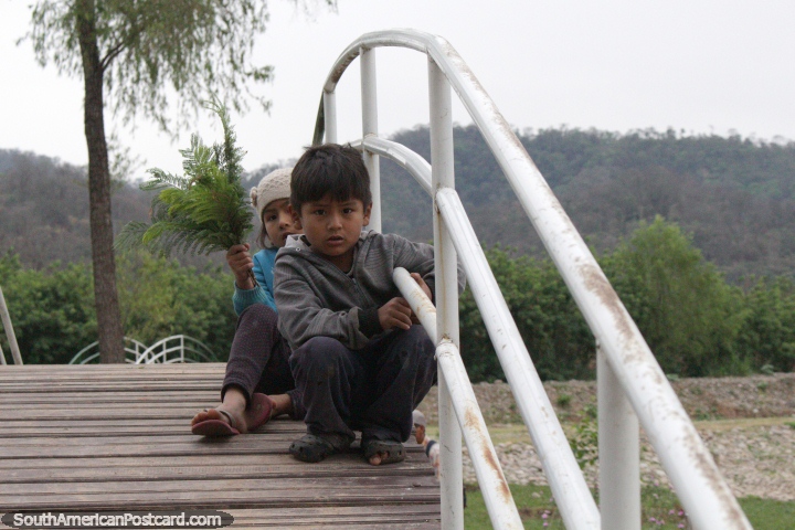 Un joven hermano y hermana se sientan en un puente en los jardines botnicos en Bermejo. (720x480px). Bolivia, Sudamerica.
