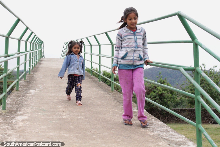 2 girls run over the bridge at the Bermejo botanical gardens. (720x480px). Bolivia, South America.