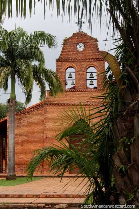 Brick church with bells and a clock, a palm tree beside, in Riberalta. (480x720px). Bolivia, South America.