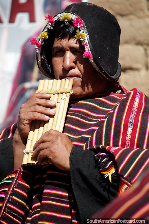 Soplando tubos de viento, hombre local de Puka-Puka en indumentaria tradicional indígena. (480x720px). Bolivia, Sudamerica.