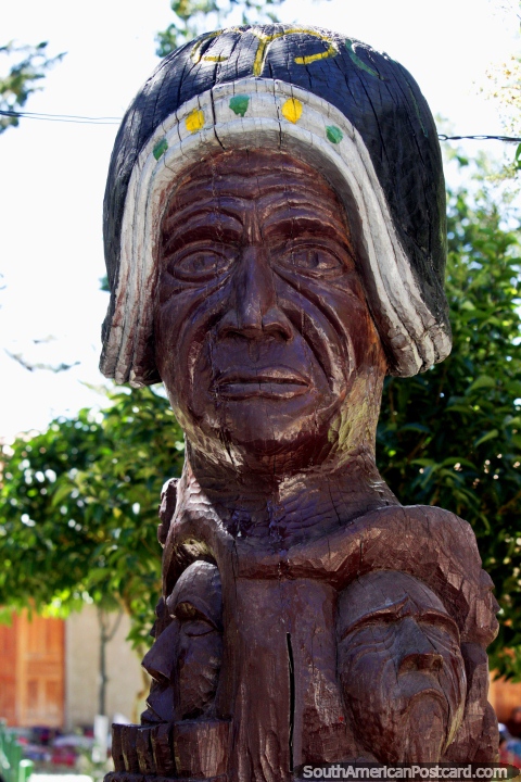 Escultura de madera de una cara grande con 2 abajo en la plaza en Tarabuco. (480x720px). Bolivia, Sudamerica.