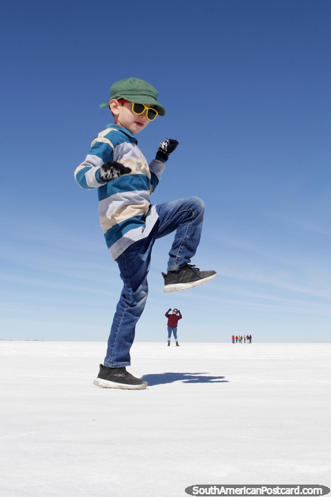 Divirta-se jogando com a perspectiva nos apartamentos de sal de Uyuni, rapaz sobre esmagar uma mulher com o seu pé. (480x720px). Bolívia, América do Sul.