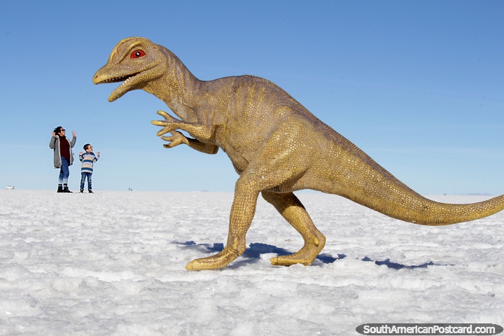 O enorme dinossauro no sai em nenhum lugar e assusta os prazeres vivos fora destas 2 gentes inocentes pobres nos apartamentos de sal de Uyuni. (720x480px). Bolvia, Amrica do Sul.