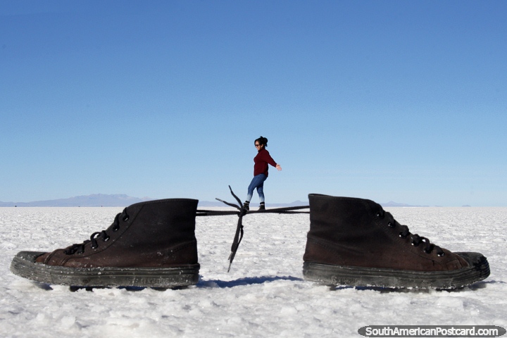 Woman walks across the tied laces of a pair of shoes, a great photo showing perspective tricks in photography at the Uyuni salt flats. (720x480px). Bolivia, South America.