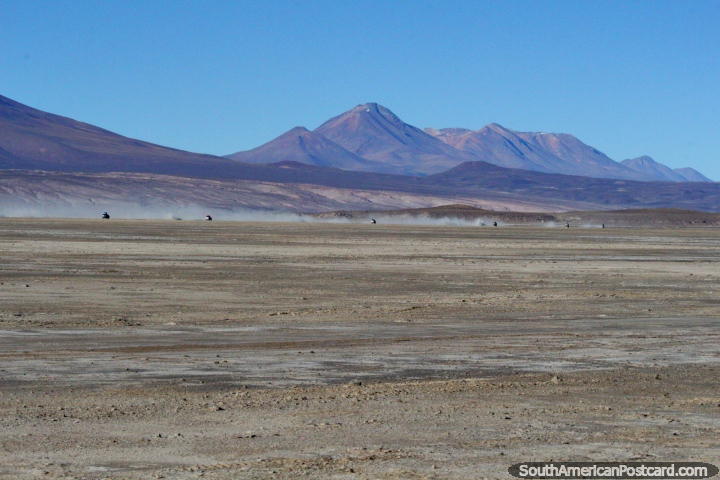 Día 2 de la excursión de 3 días en el desierto de Uyuni, un convoy de jeeps en la distancia que se dirige a las montañas. (720x480px). Bolivia, Sudamerica.