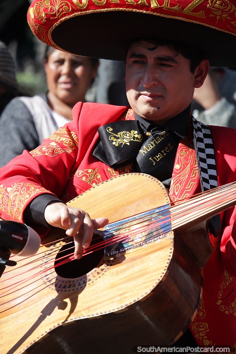 Man dressed in red with large hat plays guitar, the Gran Poder festival begins in Sucre. (480x720px). Bolivia, South America.