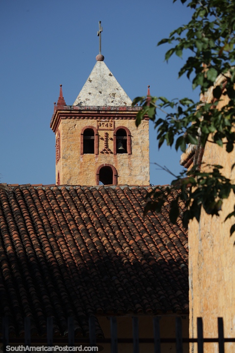 Torre da igreja atrs de um telhado em San Jose de Chiquitos. (480x720px). Bolvia, Amrica do Sul.
