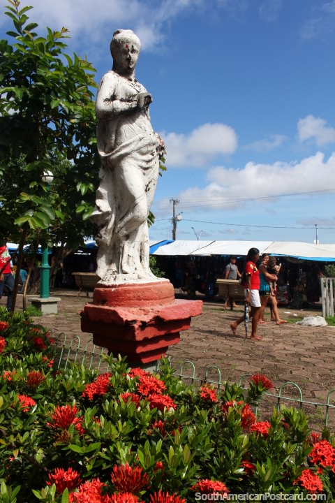 Una figura femenina en un jardín de flores rojas en la plaza frente a la catedral de Santarem. (480x720px). Brasil, Sudamerica.