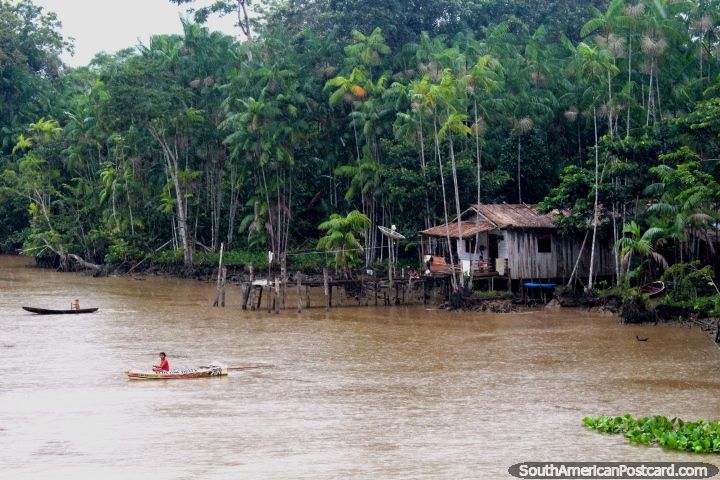 A mother and child in separate canoes outside their house in the Amazon, north of Breves. (720x480px). Brazil, South America.