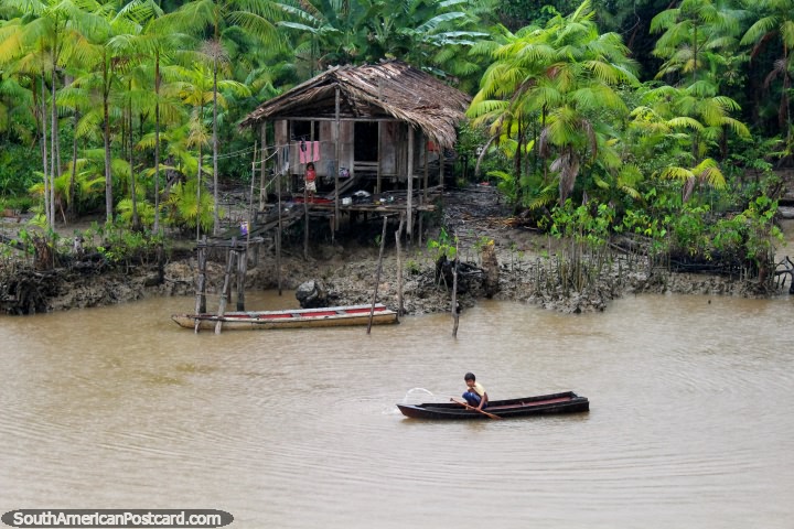 2 niños fuera de su casa en la selva Amazónica, uno está en una canoa. (720x480px). Brasil, Sudamerica.
