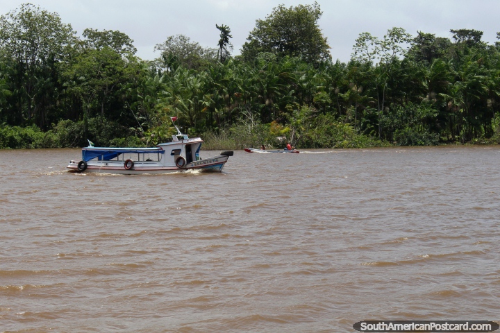 A small passenger boat and a river canoe cross paths west of Belem. (720x480px). Brazil, South America.