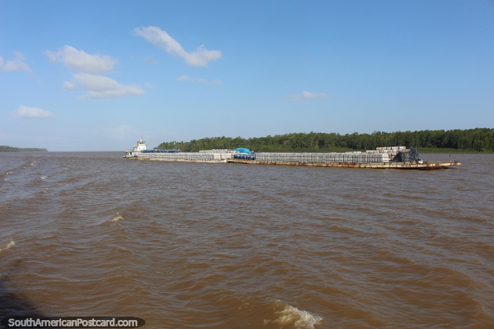 Tugboat pushes a long barge of cargo along the river in the Amazon, west of Belem. (720x480px). Brazil, South America.