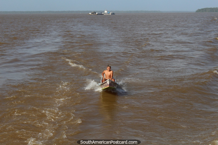 An Amazon boy on a motorized canoe chases the ferry, Belem to Macapa. (720x480px). Brazil, South America.