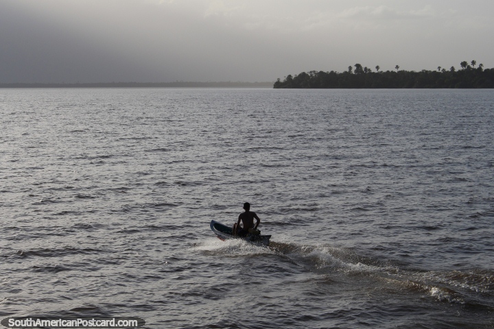 O rapaz em uma canoa impede no ocaso no fim de dias na viagem de Belém a Macapa. (720x480px). Brasil, América do Sul.