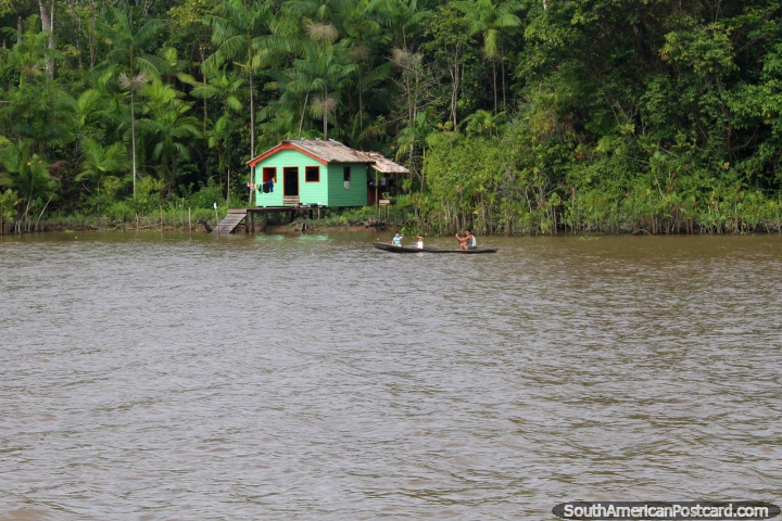 Famlia em uma canoa no rio do lado de fora da sua pequena casa de Amaznia verde, ao sul de Macapa. (720x480px). Brasil, Amrica do Sul.