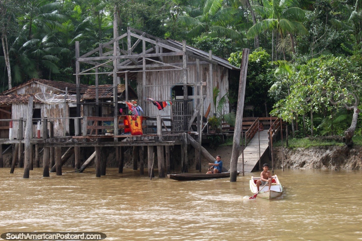Pai e filho, cada um em uma canoa do lado de fora da sua casa de Amazônia, ao sul de Macapa. (720x480px). Brasil, América do Sul.