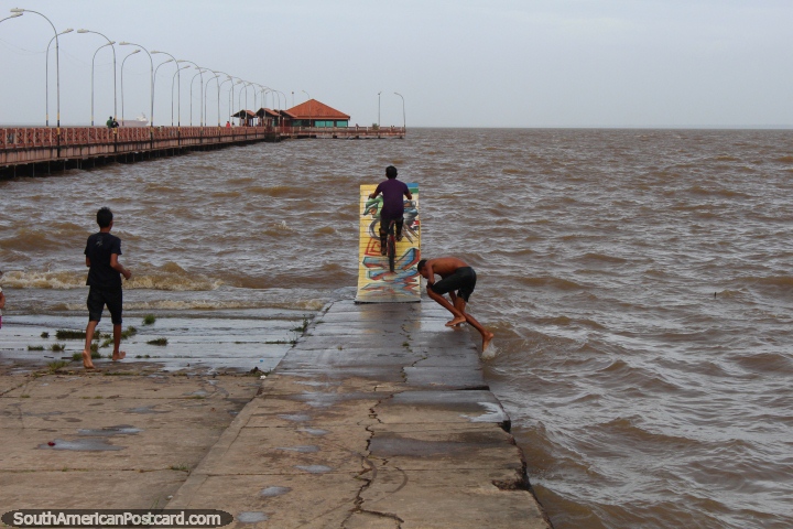 Boy rides a bike on a ramp into the Amazon River in Macapa. (720x480px). Brazil, South America.