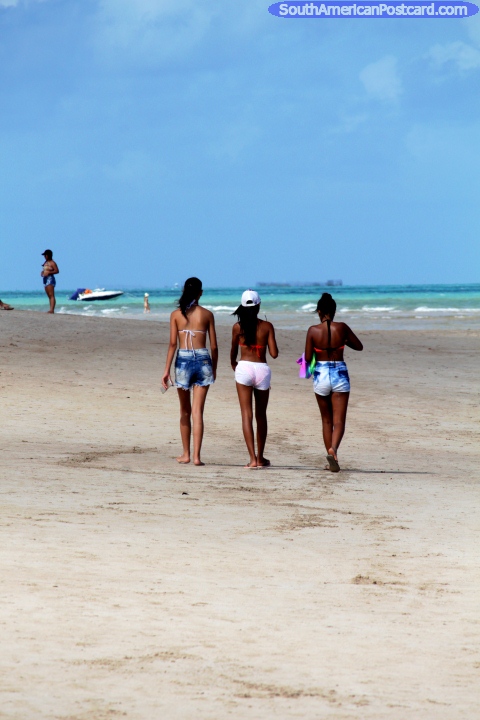 3 mujeres jóvenes que caminan a lo largo de la playa en Maragogi, arena blanca. (480x720px). Brasil, Sudamerica.