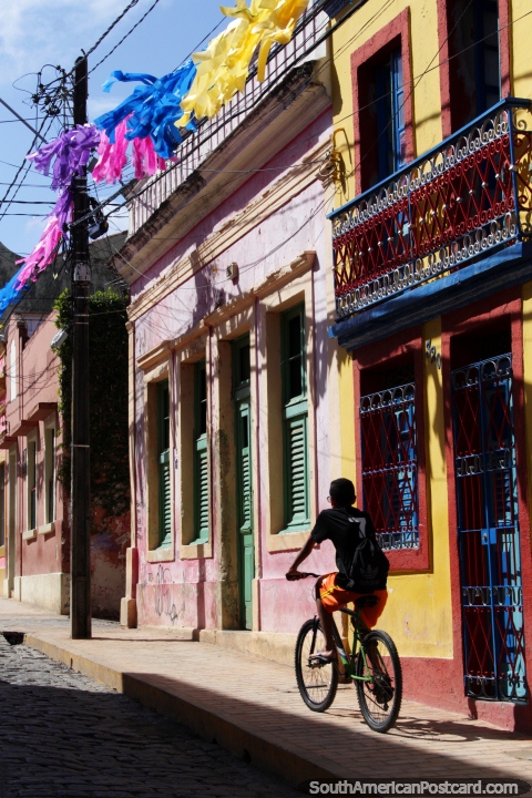 Man rides a bike up the old streets of Olinda, iron balcony and cobblestone street. (480x720px). Brazil, South America.