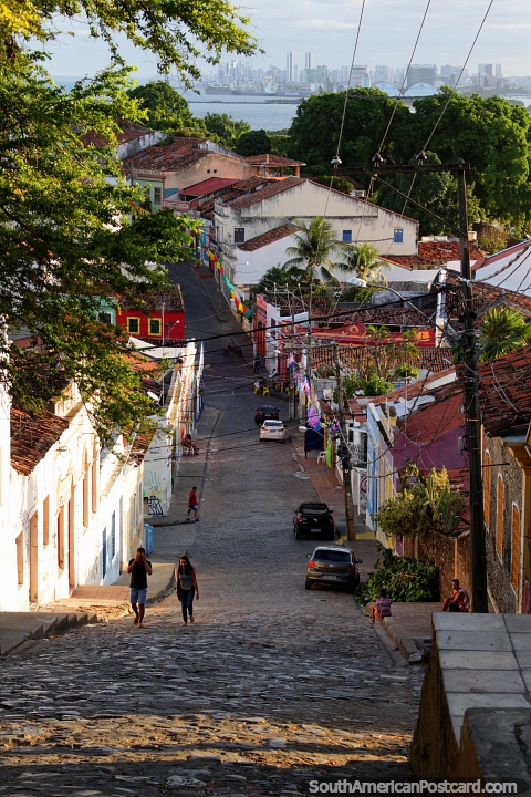 Long and steep cobblestone road leading up the hill in Olinda, Recife in the distance. (480x720px). Brazil, South America.
